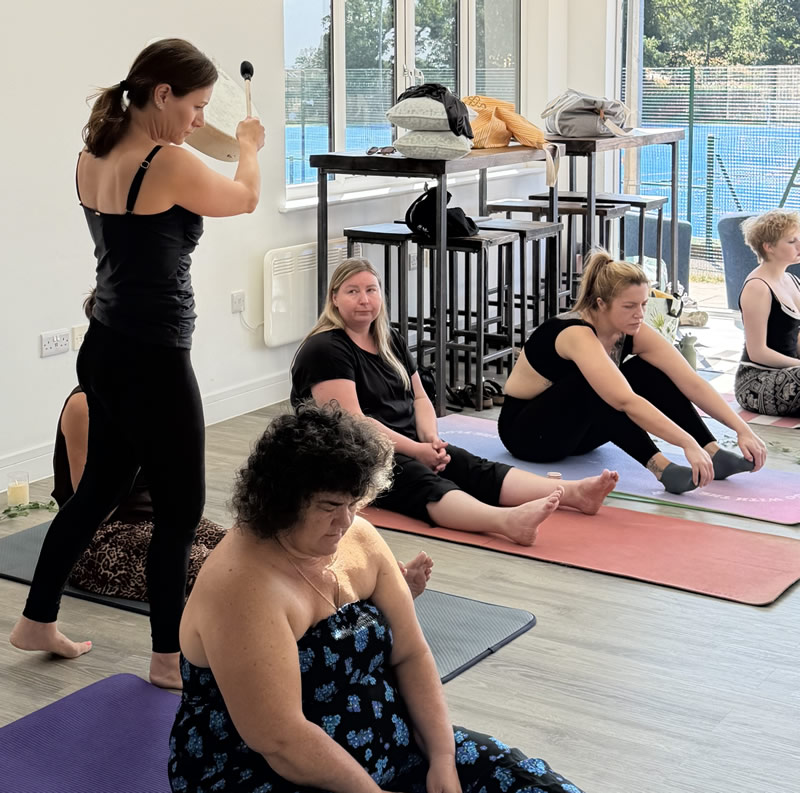 retreat leader plays sounds while moving through participants sat on yoga mats